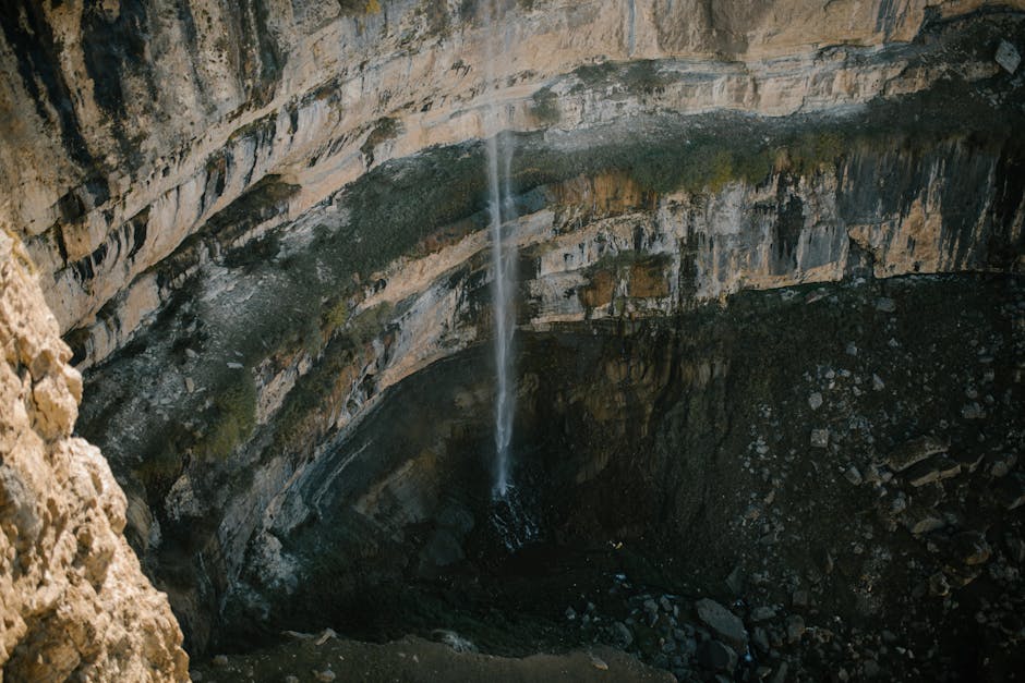 A breathtaking aerial view of a waterfall cascading down a rugged canyon, showcasing nature's raw beauty.
